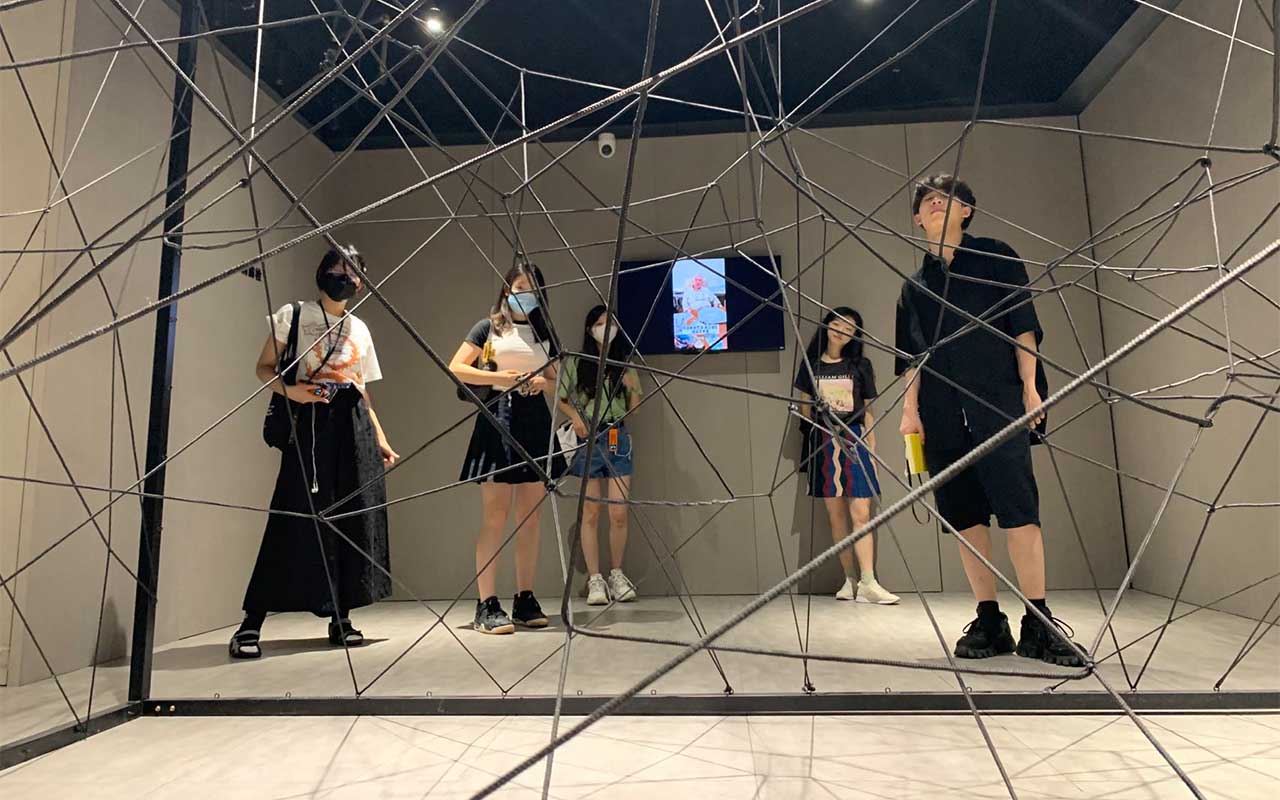 Teenage students examining room-sized sculpture in an art gallery.