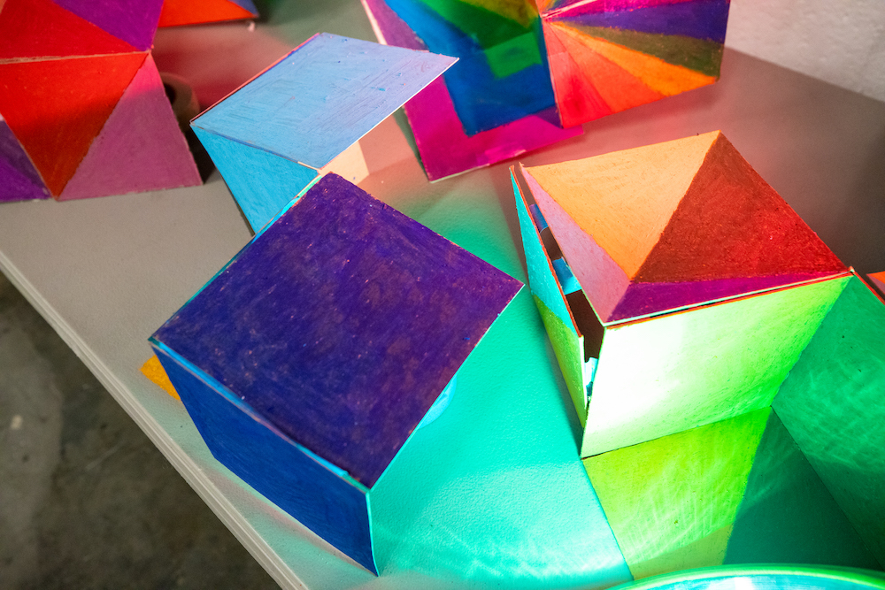 Colored cardboard boxes with light shining on them.