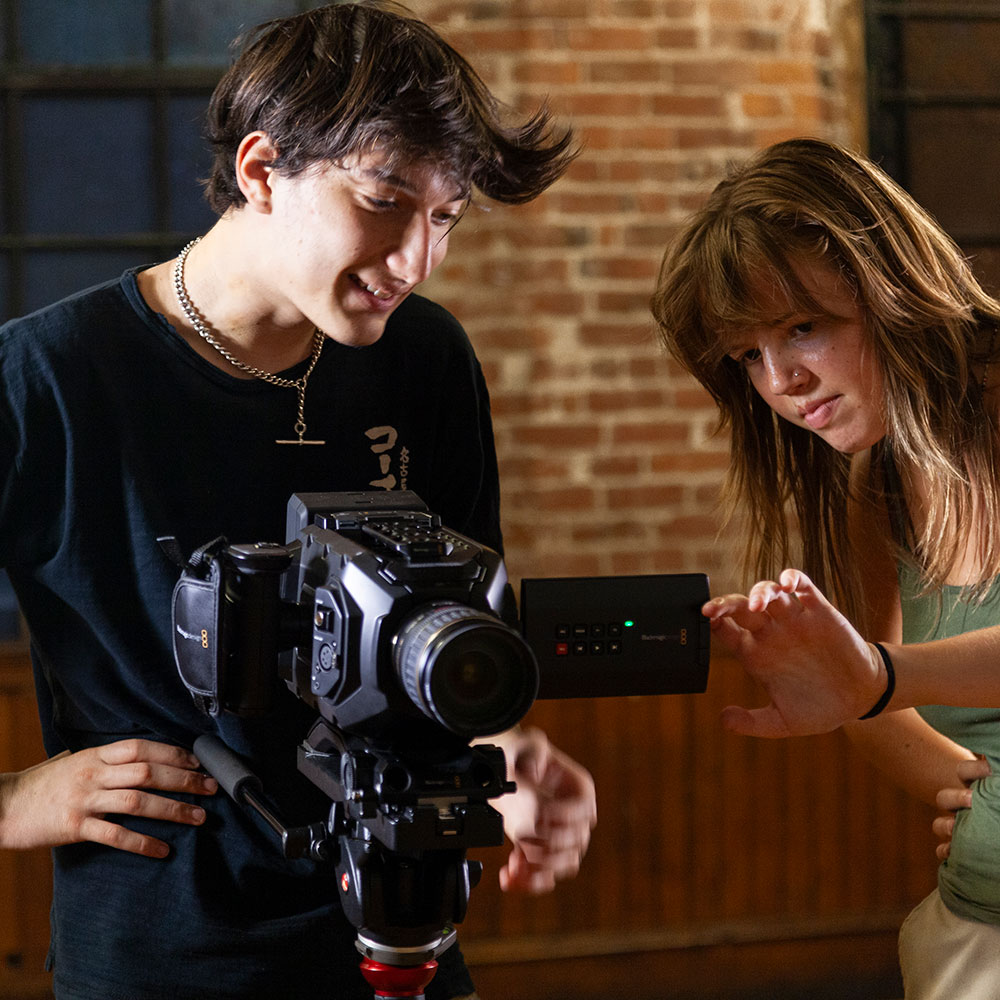 Teenage boy and girl working with a video camera.