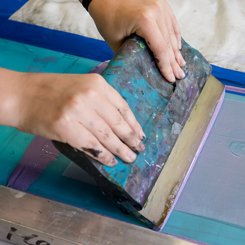 A person screen printing.