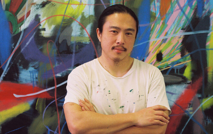 Portrait photo of instructor Yikui (Coy) Gu in front of an abstract wall painting.