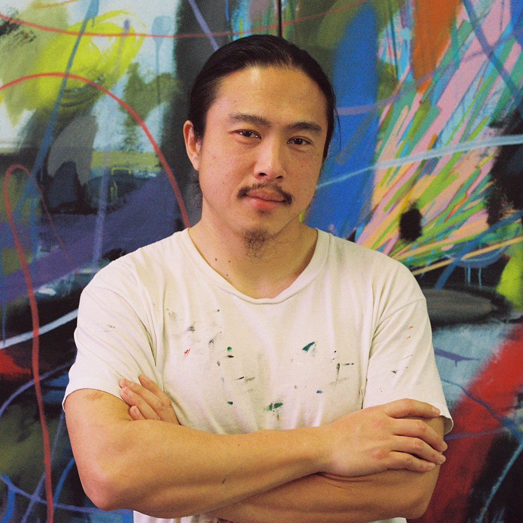risdce-instructor-spotlight-Yikui-Coy-Gu-sq Portrait of RISD CE instructor Yikui (Coy) Gu standing in front of a wall with abstract painting.