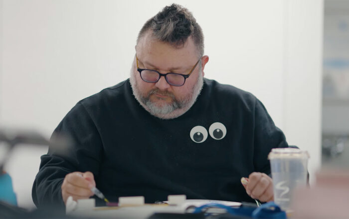 A man holding a paint brush while sitting at a table.