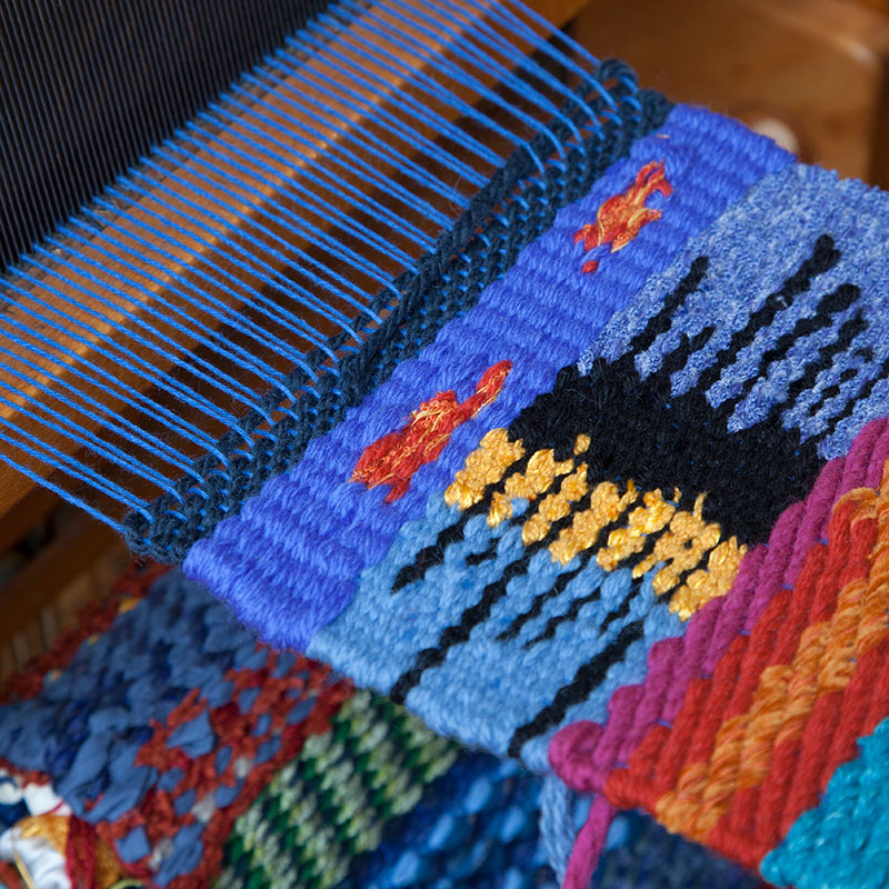A rug being woven on a hand loom.