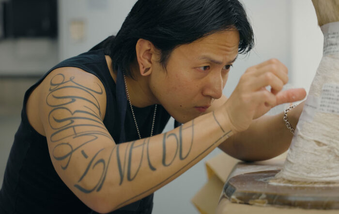 A man works on a sculpture project using gauze tape.