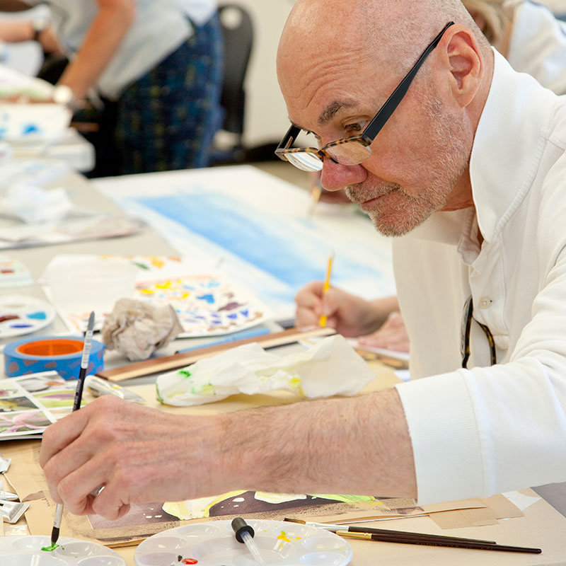 risdce_painting_land_and_sea A man paints with watercolors.