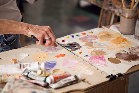 student mixing paint on a palette with a palette knife