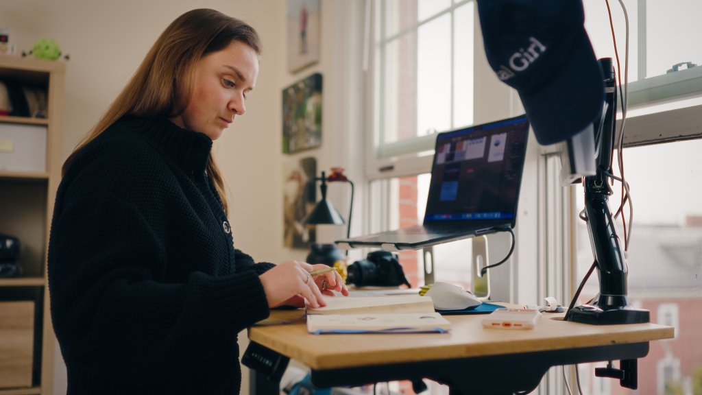 Woman at desk writing on paper.